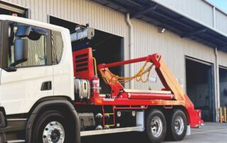 Skip loader truck in front of garage